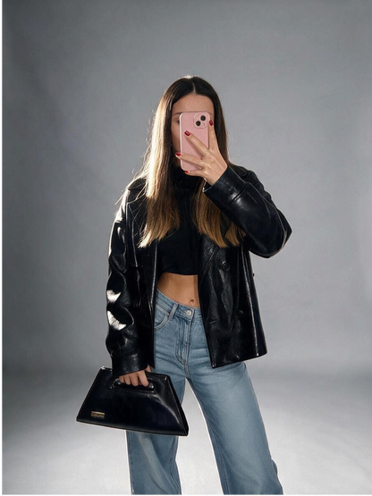 Modella con borsa Amatì Star nera in ecopelle naplak effetto vernice con manico intagliato e placchetta dorata