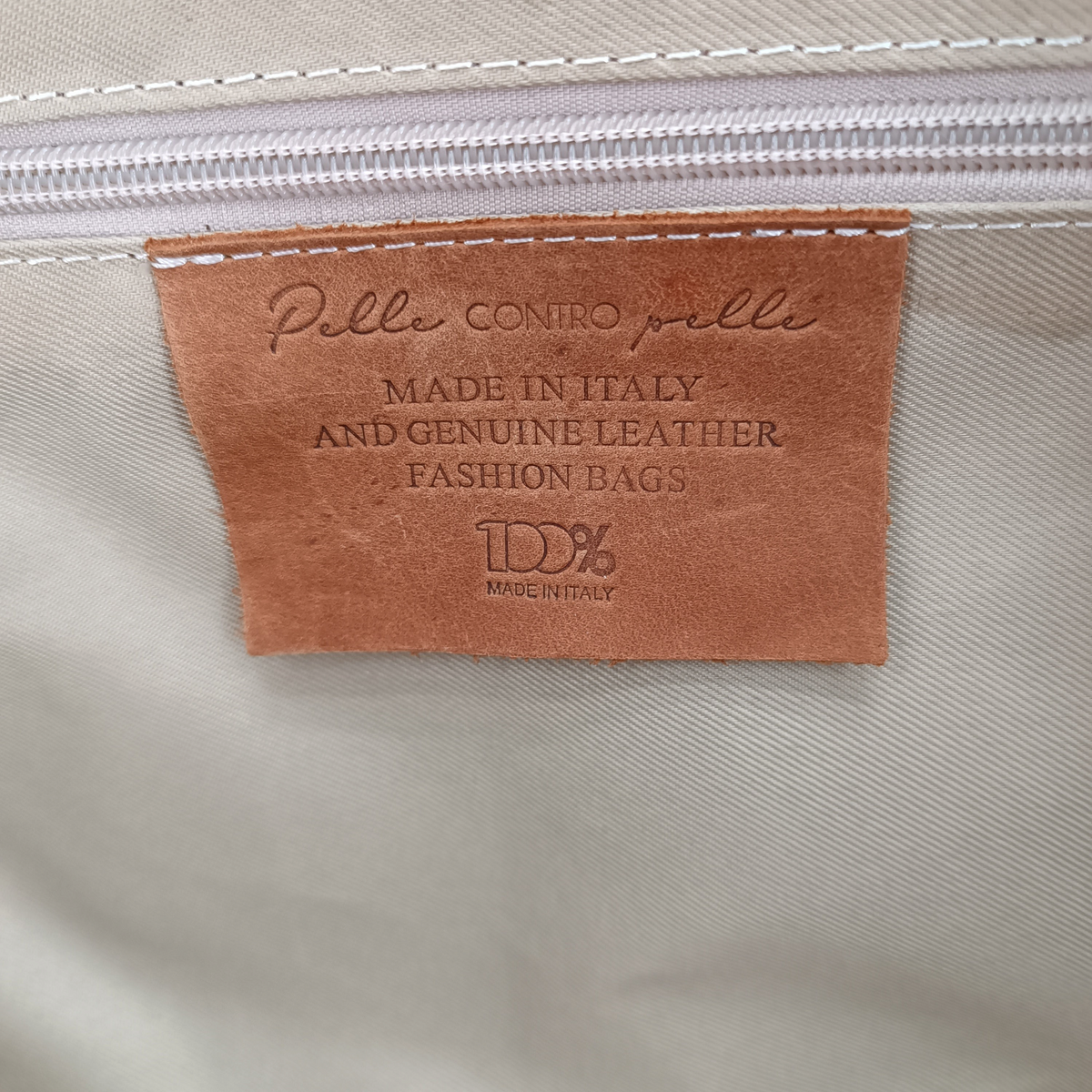 Etichetta interna in pelle del borsone Amatì Apollo con scritta Made in Italy e 100% vera pelle su fodera chiara